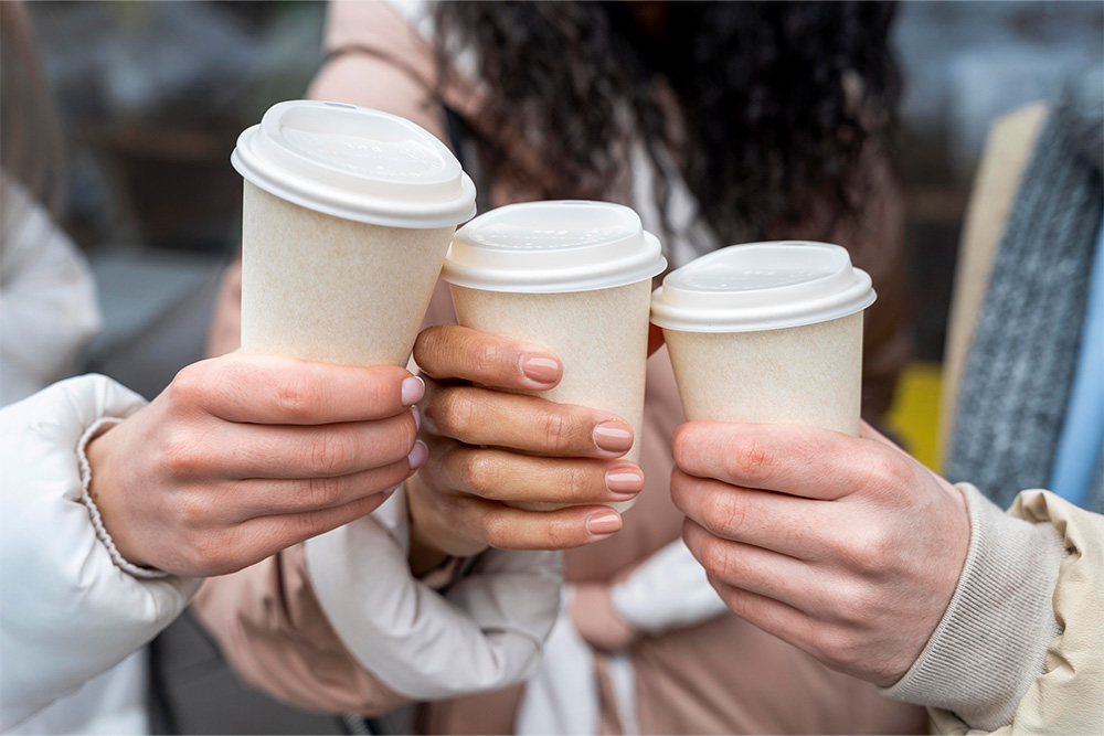 Drei Hände halten Kaffeebecher