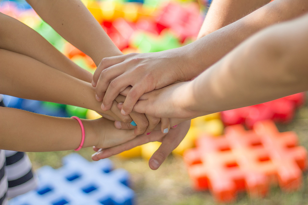 Kinder legen die Hände aufeinander