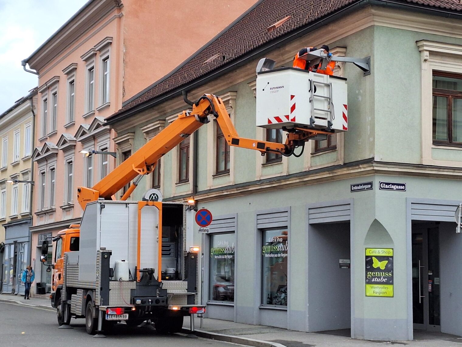 Mitarbeiter des Wirtschaftshos installieren Leuchtmittel an Straßenlaterne